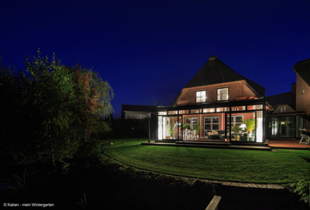 Wintergarten-mit-Haus-beleuchtet-bei-Nacht